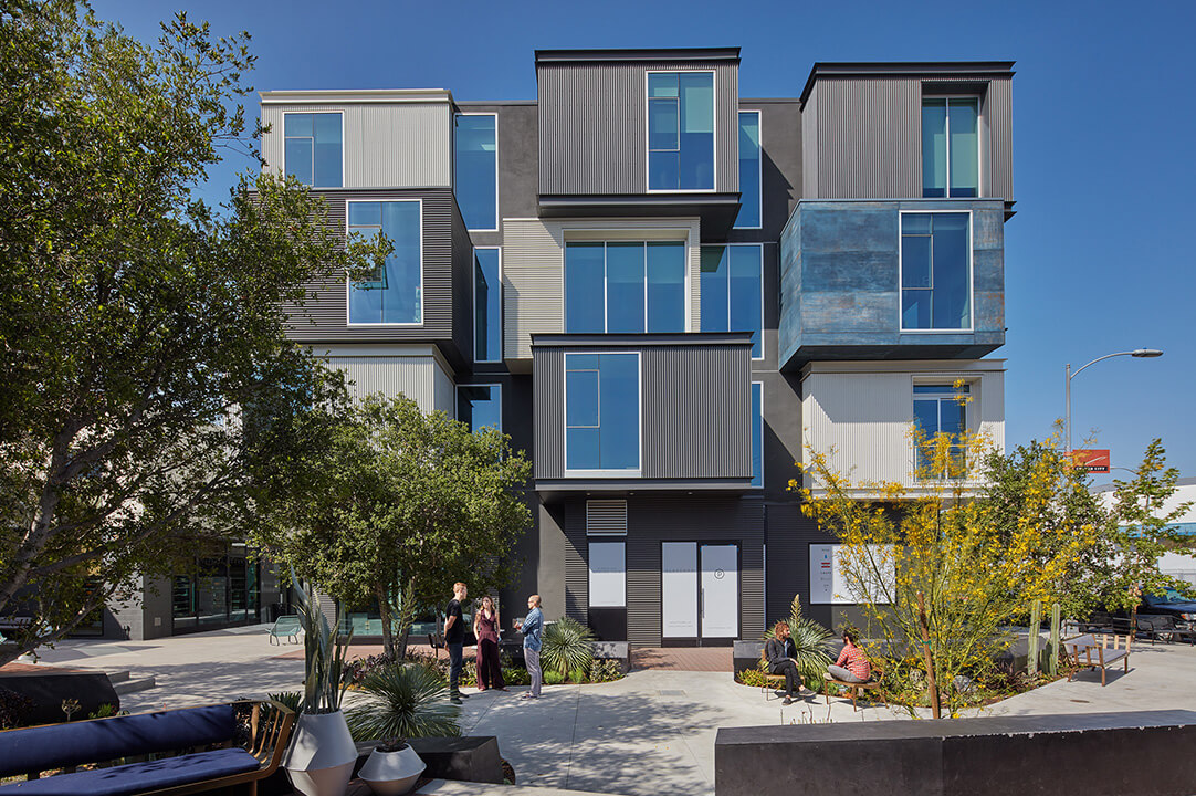 Modern apartments with geometric design and trees in the foreground.